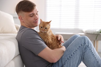 Photo of Man with cute ginger cat at home