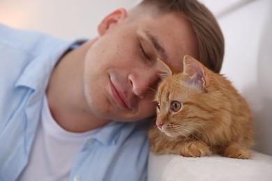 Photo of Man with cute ginger cat at home, selective focus