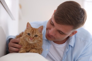 Photo of Man with cute ginger cat at home