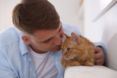 Photo of Man with cute ginger cat at home