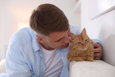Photo of Man with cute ginger cat at home