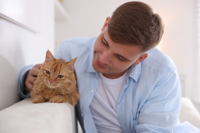 Photo of Man with cute ginger cat at home