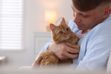 Photo of Man with cute ginger cat at home, space for text