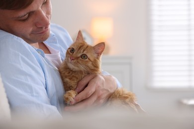 Photo of Man with cute ginger cat at home