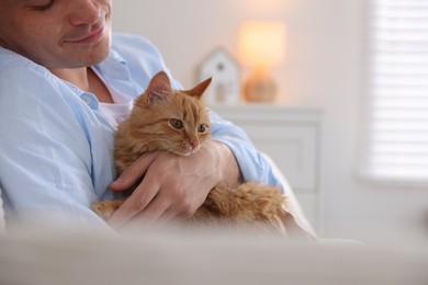 Photo of Man with cute ginger cat at home