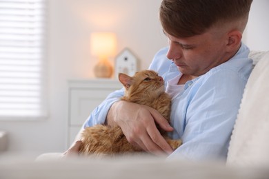 Photo of Man with cute ginger cat on sofa at home