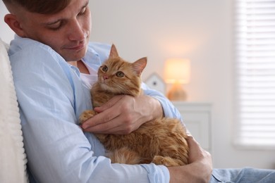 Photo of Man with cute ginger cat at home