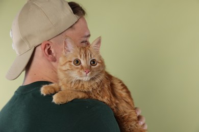 Photo of Man with cute ginger cat on light green background, space for text