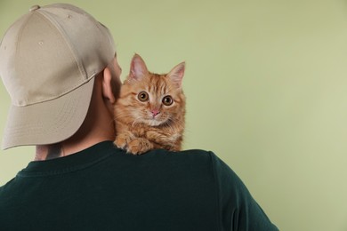Photo of Man with cute ginger cat on light green background, space for text