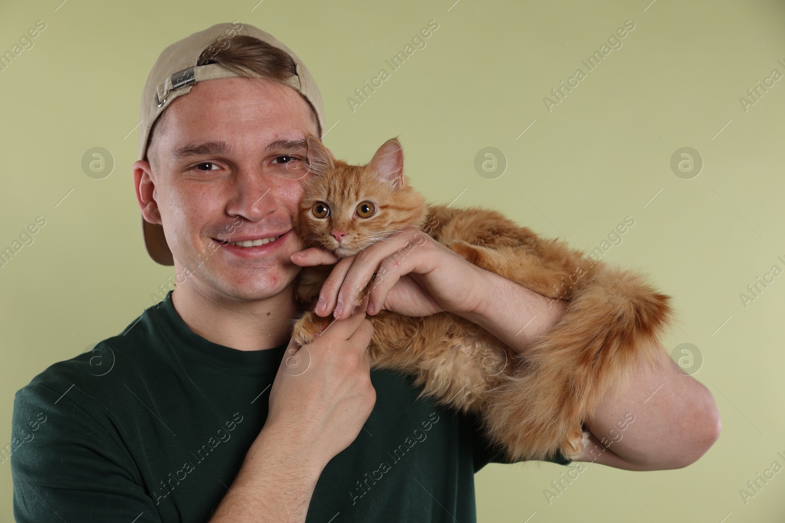 Man with cute ginger cat on light green background Photo of Man with cute ginger cat on light green background