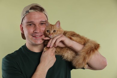 Photo of Man with cute ginger cat on light green background