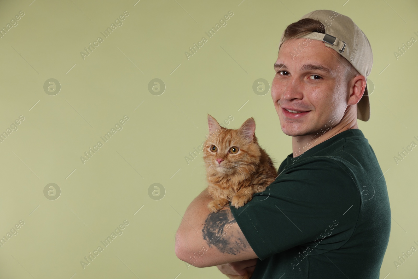 Man with cute ginger cat on light green background, space for text Photo of Man with cute ginger cat on light green background, space for text