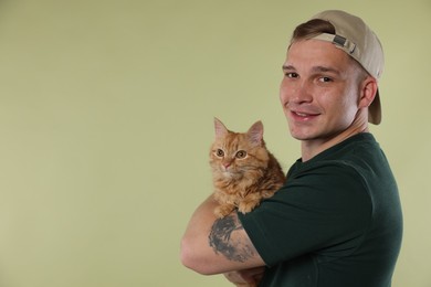 Photo of Man with cute ginger cat on light green background, space for text