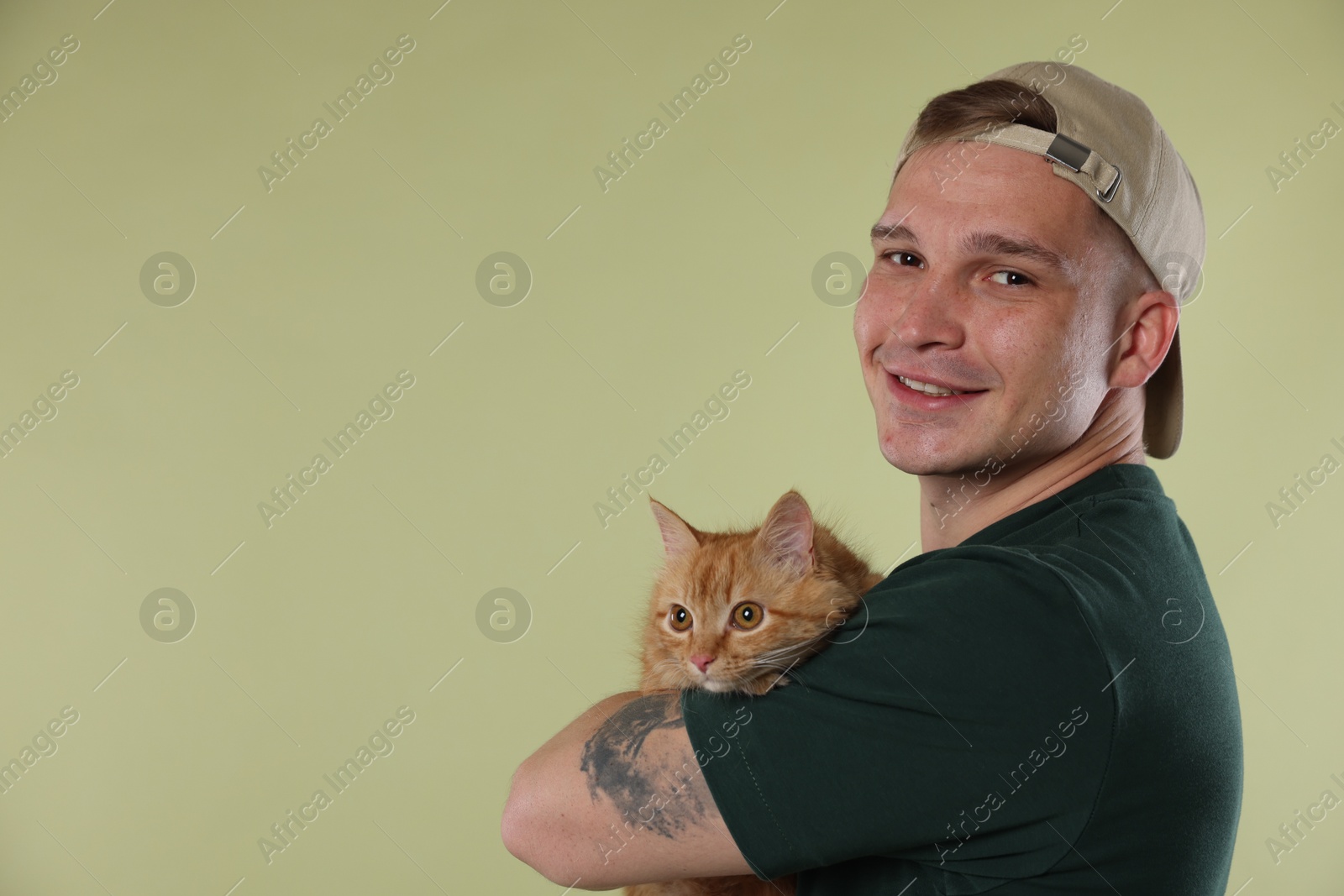 Man with cute ginger cat on light green background, space for text Photo of Man with cute ginger cat on light green background, space for text