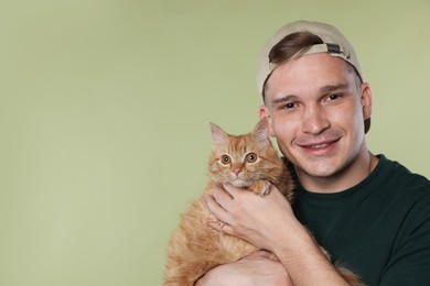 Photo of Man with cute ginger cat on light green background, space for text