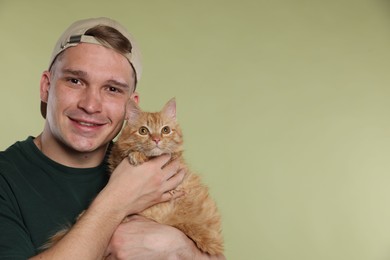 Photo of Man with cute ginger cat on light green background, space for text