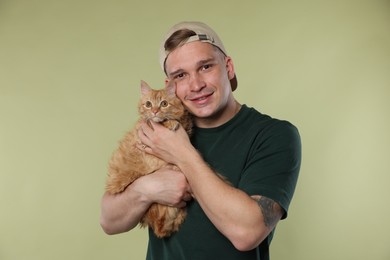 Photo of Man with cute ginger cat on light green background
