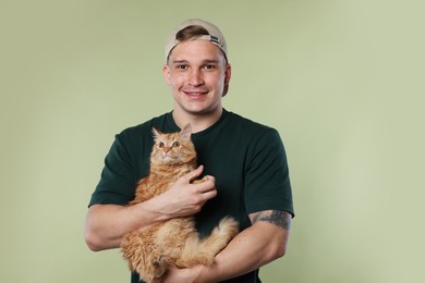Photo of Man with cute ginger cat on light green background