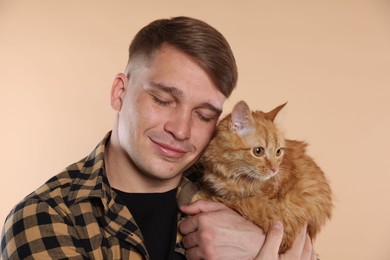 Photo of Man with cute ginger cat on beige background