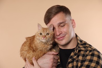 Photo of Man with cute ginger cat on beige background