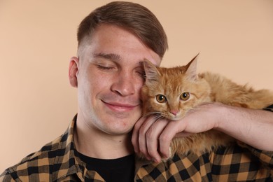 Photo of Man with cute ginger cat on beige background
