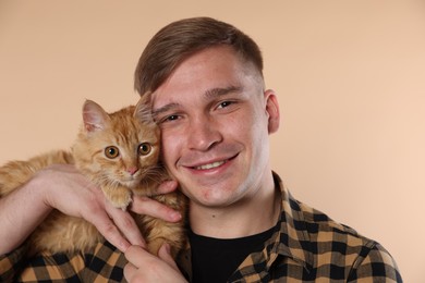 Photo of Man with cute ginger cat on beige background