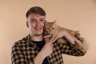 Photo of Man with cute ginger cat on beige background