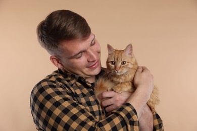 Photo of Man with cute ginger cat on beige background