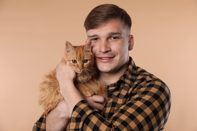 Photo of Man with cute ginger cat on beige background