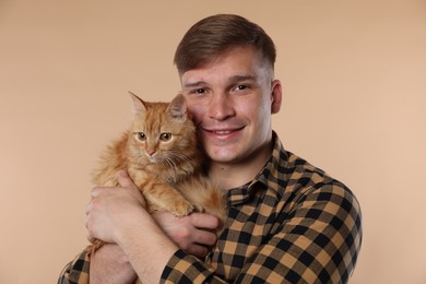 Photo of Man with cute ginger cat on beige background