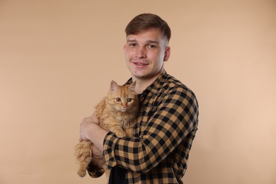 Photo of Man with cute ginger cat on beige background