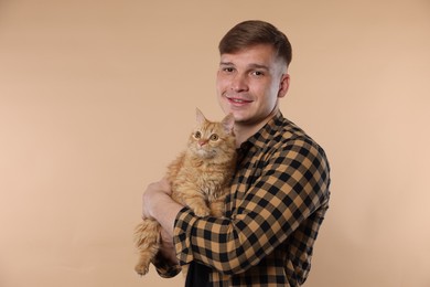 Photo of Man with cute ginger cat on beige background