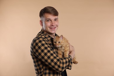 Photo of Man with cute ginger cat on beige background