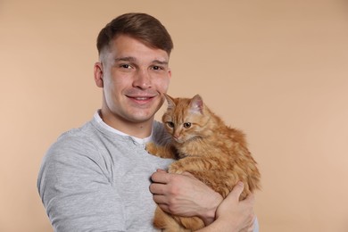Photo of Man with cute ginger cat on beige background