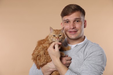 Photo of Man with cute ginger cat on beige background