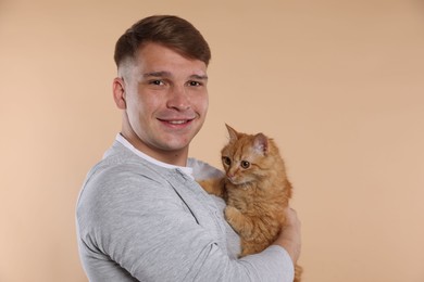 Photo of Man with cute ginger cat on beige background