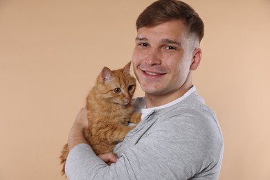 Photo of Man with cute ginger cat on beige background