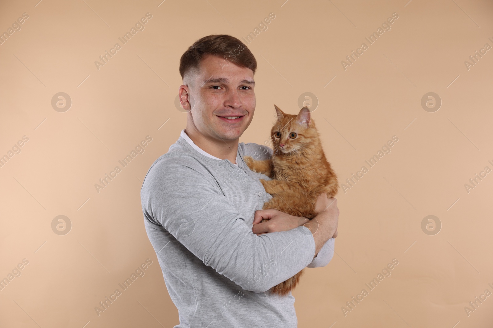 Man with cute ginger cat on beige background Photo of Man with cute ginger cat on beige background