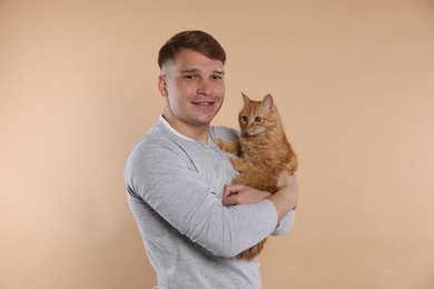 Photo of Man with cute ginger cat on beige background