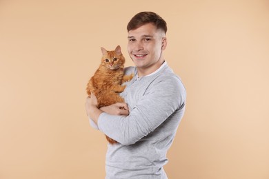 Photo of Man with cute ginger cat on beige background