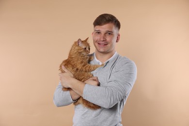 Photo of Man with cute ginger cat on beige background
