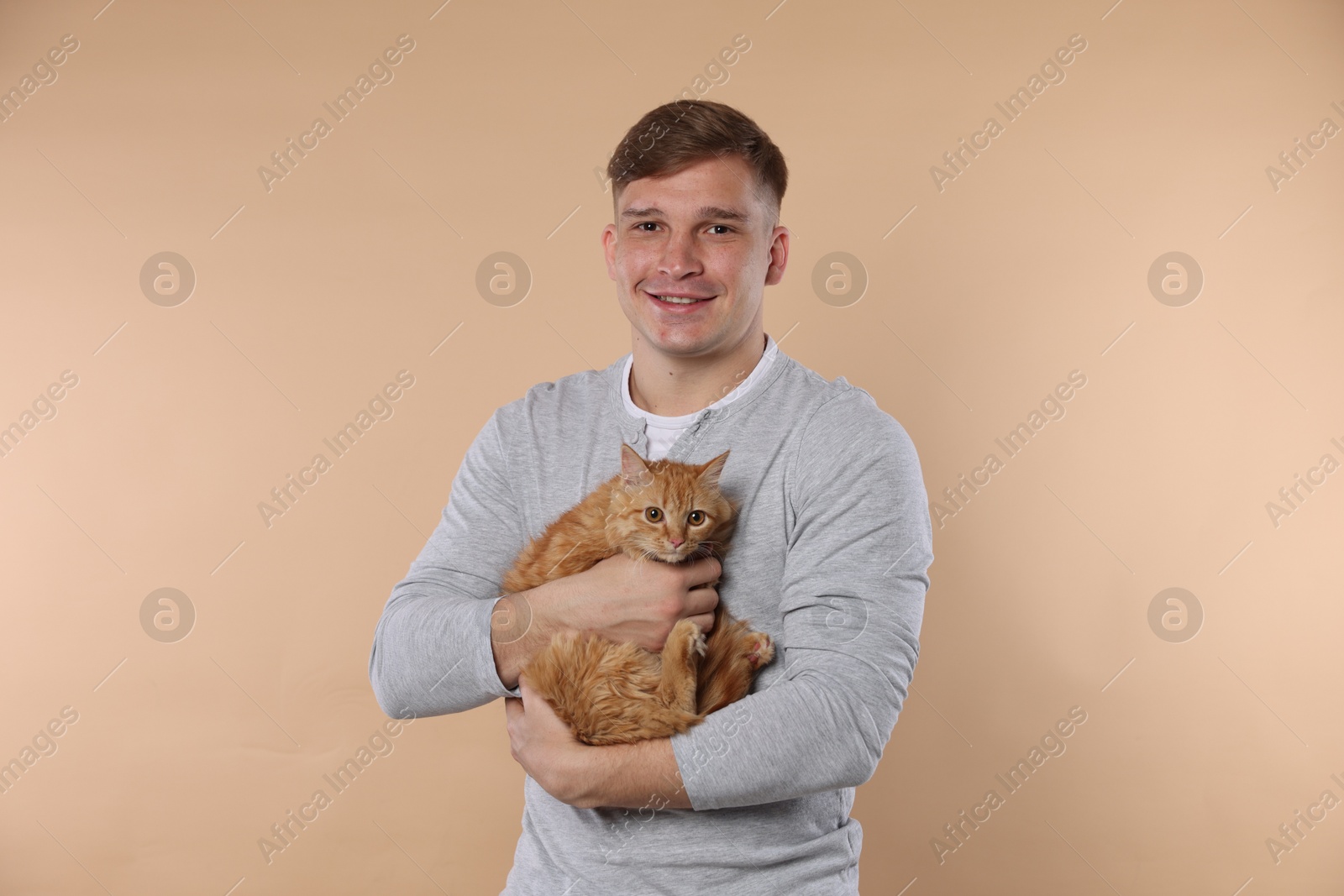 Man with cute ginger cat on beige background Photo of Man with cute ginger cat on beige background