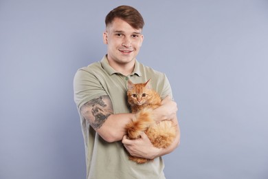 Photo of Man with cute ginger cat on gray background
