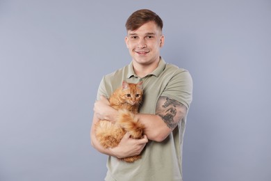 Photo of Man with cute ginger cat on gray background
