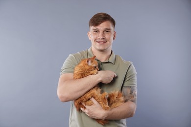 Photo of Man with cute ginger cat on gray background