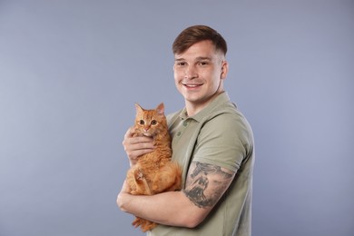 Photo of Man with cute ginger cat on gray background