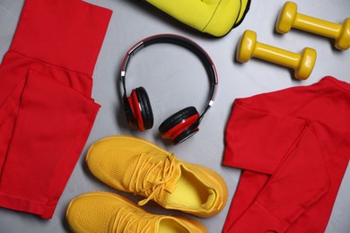 Photo of Sportswear, sneakers, ankle weights, dumbbells and headphones on gray textured background, flat lay