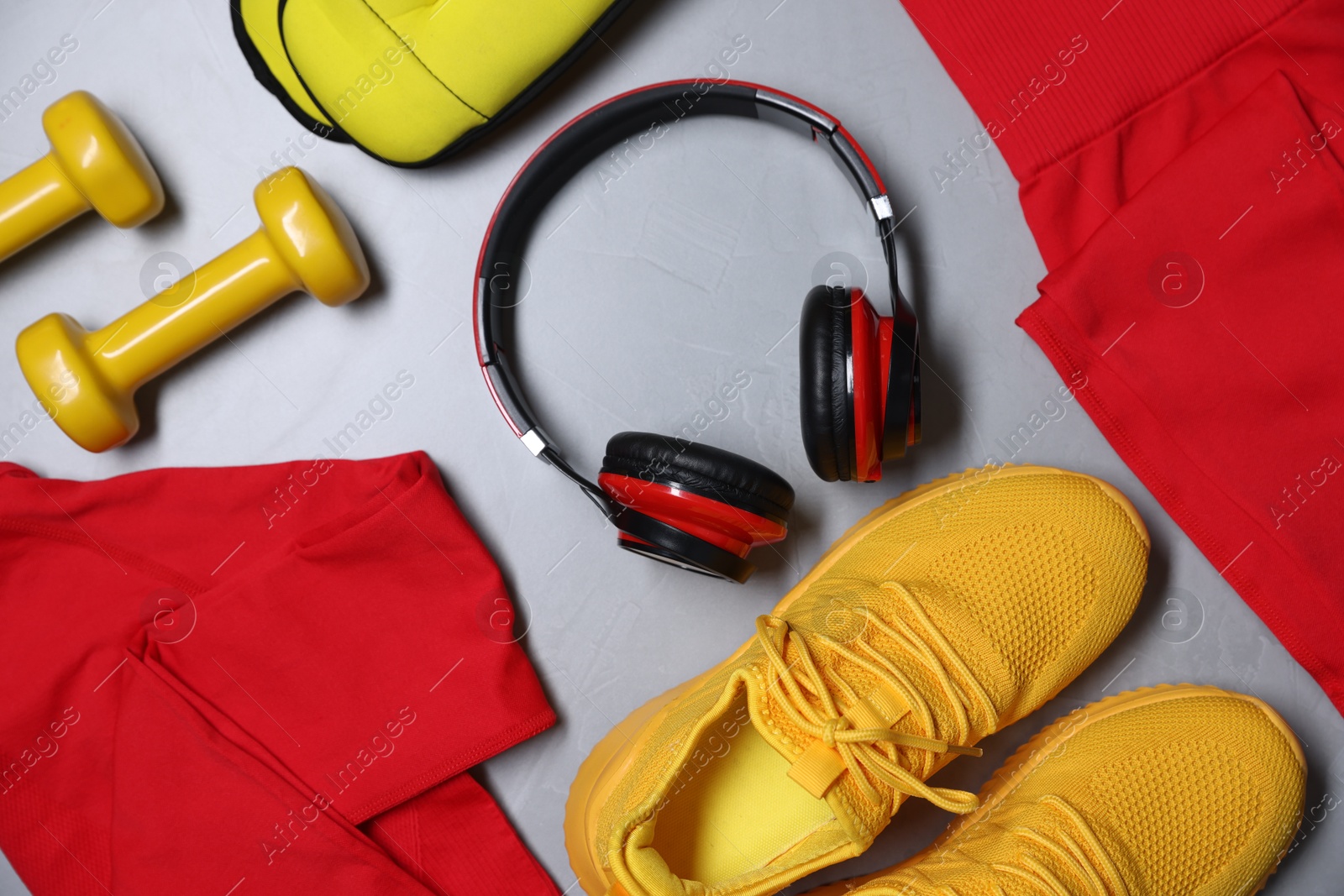 Sportswear, sneakers, ankle weights, dumbbells and headphones on gray textured background, flat lay Photo of Sportswear, sneakers, ankle weights, dumbbells and headphones on gray textured background, flat lay