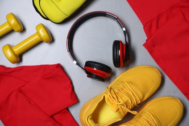 Photo of Sportswear, sneakers, ankle weights, dumbbells and headphones on gray textured background, flat lay