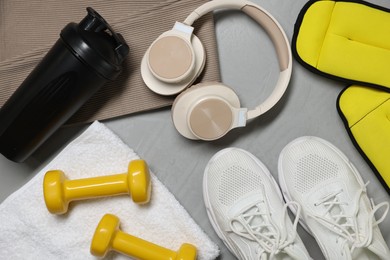 Photo of Sportswear, sneakers, headphones and other accessories on gray textured background, flat lay